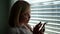 Close-up portrait of a pleasant middle-aged woman with short blond hair, sitting in an office near the blinds and