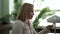 A close-up portrait of a pleasant middle-aged woman with short blond hair sitting in an office and talking on a tablet