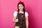 Close up portrait of pleased young housewife finishes making chocolate cake. Attractive girl soiled with flour looks happy, stands