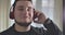 Close-up portrait of plump Caucasian man enjoying music in headphones. Happy young guy listening to music in earphones