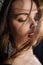 Close-up portrait plus size model in a gold blouse and black jeans leaned on a brick loft wall.