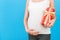 Close up portrait of pregnant woman in home clothing holding a gift box at blue background. Pregnancy celebration. Copy space