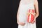 Close up portrait of pregnant woman in white dress holding a gift box at black background. Pregnancy celebration. Copy space