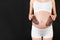 Close up portrait of pregnant woman in white underwear holding booties for baby boy at black background. Happy child expecting.