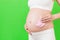 Close up portrait of pregnant woman in white underwear holding pink socks for a baby girl at green background. Waiting for a child