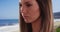 Close-up portrait of pretty brunette deep in thought in serene beach setting