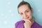 Close up portrait of pretty delighted young woman holds chin, looks positively at camera, enjoys having weekend, dressed in purple