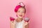 Close-up portrait of pretty girl with pink hairstyle with dragon fruit on pink background. Studio shot of charming tween