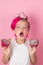 Close-up portrait of pretty girl with pink hairstyle with dragon fruit on pink background. Studio shot of charming tween