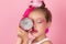 Close-up portrait of pretty girl with pink hairstyle with dragon fruit on pink background. Studio shot of charming tween