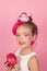 Close-up portrait of pretty girl with pink hairstyle with dragon fruit on pink background. Studio shot of charming tween