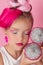 Close-up portrait of pretty girl with pink hairstyle with dragon fruit on pink background. Studio shot of charming tween