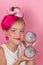 Close-up portrait of pretty girl with pink hairstyle with dragon fruit on pink background. Studio shot of charming tween