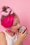 Close-up portrait of pretty girl with pink hairstyle with dragon fruit on pink background. Studio shot of charming tween