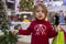 Close-up portrait of a pretty little girl in a red sweater with gifts on a christmas background. shopping mall on