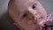 Close-up portrait of pretty newborn girl lying on sofa and watching into camera intently.