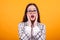 Close up portrait of pretty teenage girl with amazed facial expression in studio over yellow background