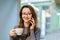 Close-up portrait of pretty young smiling woman sitting in the cafe with a cup of tea or coffee, window on the