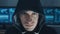 Close up Portrait of IT professional Hacker programmer in black hoody at cyber security center filled with display