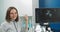 Close up portrait of professional smiling young woman doctor sonographer sitting near modern ultrasound scanner machine