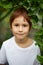 Close-up portrait of redhead child boy around green plants