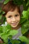 Close-up portrait of redhead child boy around green plants
