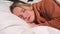 Close up portrait of relaxed woman sleeping on a white pillow in bed. Portrait of young Caucasian woman resting in