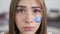 Close-up portrait of a sad crying young woman looking at the camera. Blue message box with zero painted on the girl`s