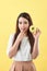 Close up portrait of a satisfied pretty girl eating donuts  over yellow background