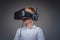 Close-up portrait of a schoolboy dressed in a white t-shirt standing in a virtual reality glasses at a studio.