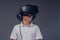 Close-up portrait of a schoolboy dressed in a white t-shirt standing in a virtual reality glasses at a studio. Isolated