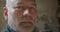 Close-up portrait of senior carpenter at wood manufacture watching into camera being serious and calm.