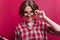 Close-up portrait of sensual stylish woman in checkered shirt wears glasses. Indoor photo of carefree curly girl posing