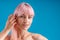 Close up portrait of sensual woman with pink hair and perfect glowing skin looking at camera, touching her hair while