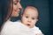 Close-up portrait of a serene cute beautiful baby boy on hands of happy smiling mother. Healthcare and medical love