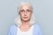 Close up portrait of serious, aged, charming woman in glasses over grey background