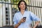 Close-up portrait of serious attractive woman with mobile phone looking away and waiting friend on the city street. Young brunette