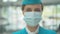 Close-up portrait of serious Caucasian stewardess in face mask looking at camera. Professional female flight attendant