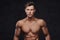 Close-up portrait of a shirtless young man model with a muscular body and stylish haircut posing at a studio