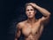 Close-up portrait of a shirtless young man model with a muscular body and stylish haircut posing at a studio