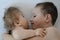 Close-up portrait of siblings looking at each other and lying on bed. Boy loves his disabled younger brother