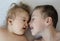 Close-up portrait of siblings looking at each other and lying on bed. Boy loves his disabled younger brother