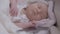 Close-up portrait sleeping calm infant lying in bed with smartphone. Carefree Caucasian baby girl napping at home