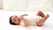 a close-up portrait of a small African-American baby girl in a white bodysuit on a cotton bed at home, a funny six-month