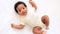 a close-up portrait of a small African-American baby girl in a white bodysuit on a cotton bed at home, a funny six-month