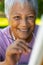 Close-up portrait of smiling biracial senior woman painting with paintbrush on canvas in yard