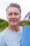 Close-up portrait of smiling caucasian senior man with blue exercise mat at tourist resort