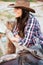 Close up portrait of a smiling cowgirl leaning on fence