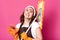 Close up portrait of smiling happy housewife looking up, holding broom and sponge in both hands with gloves. Delighted brunette