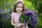 Close up portrait of a smiling little girl in pink dress and with a large bouquet of lupins. A child in a field of lupines. Childh